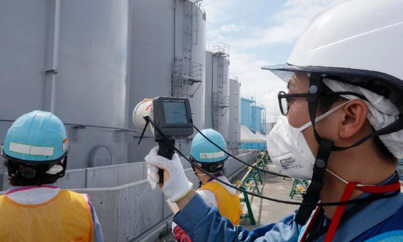 Staff measure radiation levels around the storage tanks of radiation-contaminated water at the tsunami-crippled Tokyo Electric P